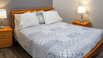 A bedroom with a bed, two bedside tables, and three framed artworks on the wall.