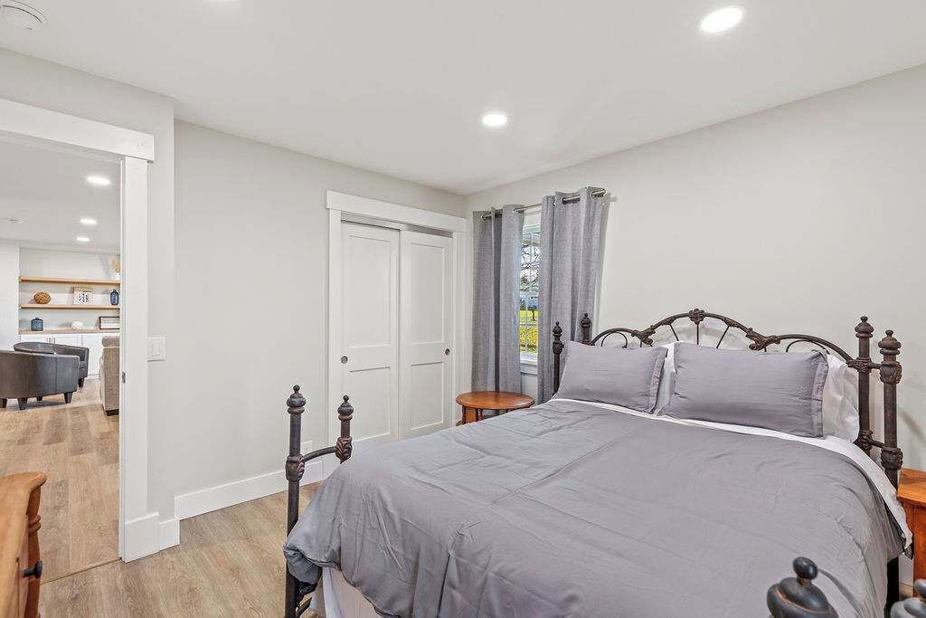 A bedroom with a large bed, a wooden headboard, a bedside table, and a door leading to a bathroom.
