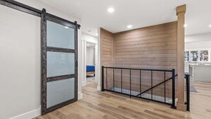 A modern interior with a wooden floor, a glass door, and a black railing.