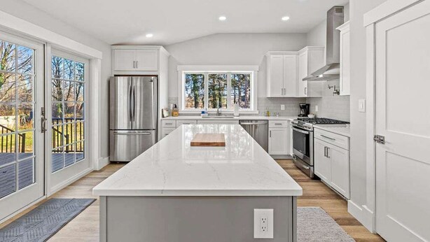 A modern kitchen with a large island, stainless steel appliances, and a view to the outdoors.