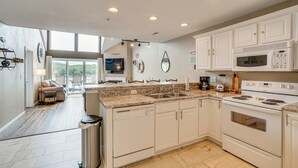 A modern kitchen with white cabinetry, a built-in oven, microwave, and a large island with a sink. - 'Lake It Easy' Waterfront Ozarks Condo w/ Balcony! (Camdenton)