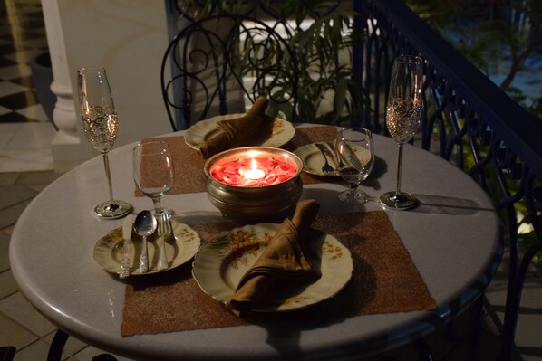 A round table with a candle centerpiece, plates, cutlery, and two glasses of champagne. - Dileep Kothi A Royal Boutique Luxury (Jaipur)