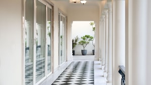 A corridor with a black and white checkered floor, white walls, and columns. - Dileep Kothi A Royal Boutique Luxury  (Jaipur)