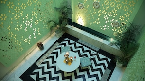 A geometric patterned floor, a central table with decorative items, and green walls with hexagonal cutouts. - Dileep Kothi A Royal Boutique Luxury  (Jaipur)