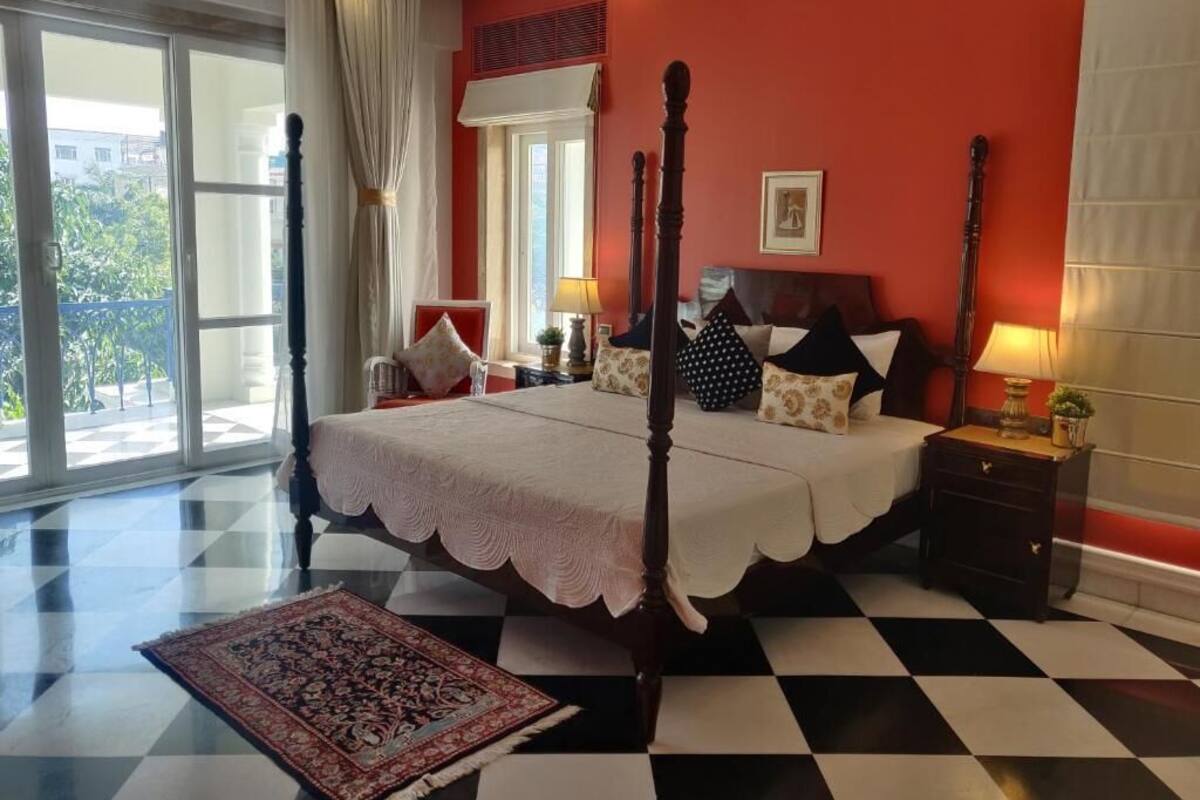 A bedroom with a four-poster bed, a checkered floor, and a large window with curtains.