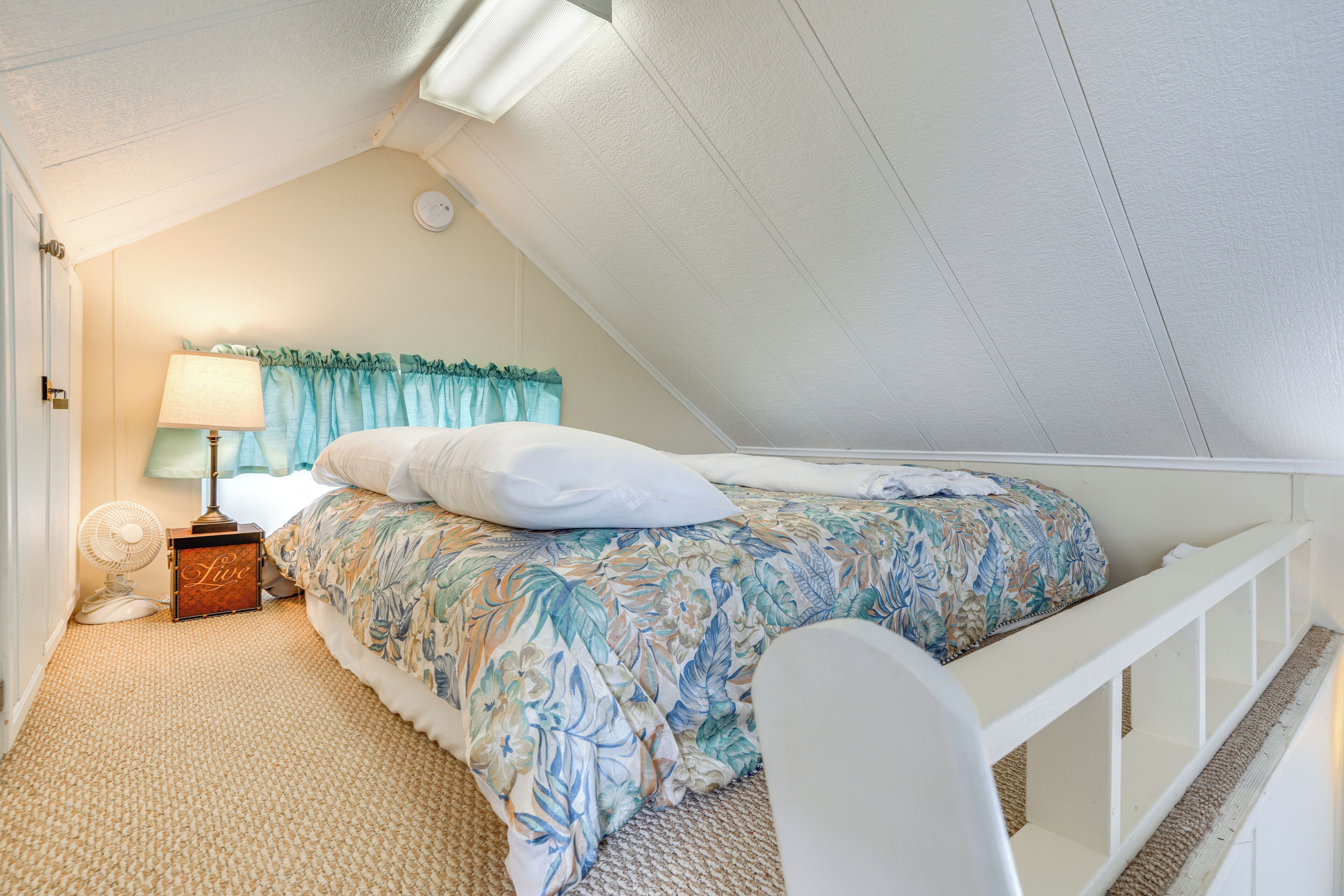 Ein Schlafzimmer mit einem Bett, einem Nachttisch, einer Lampe und einem Deckenventilator.