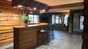 A wooden interior with a bar area, stone walls, and large windows. - Every Room with a Beautiful View of The Wisconsin River * (Tomahawk)