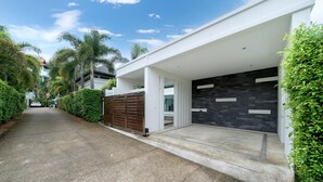 A modern house with a covered driveway, a garage with a black tiled wall, and a gated entrance. - Villa Talosy with Salt Pool near NaiHarn (Rawai)