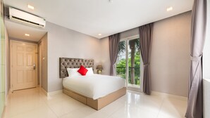 A modern bedroom with a large bed, a built-in headboard, a window with curtains, and an air conditioning unit.