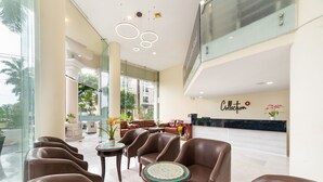 A spacious lobby with leather seating, a reception desk, and a large window offering a view of the outdoors.
