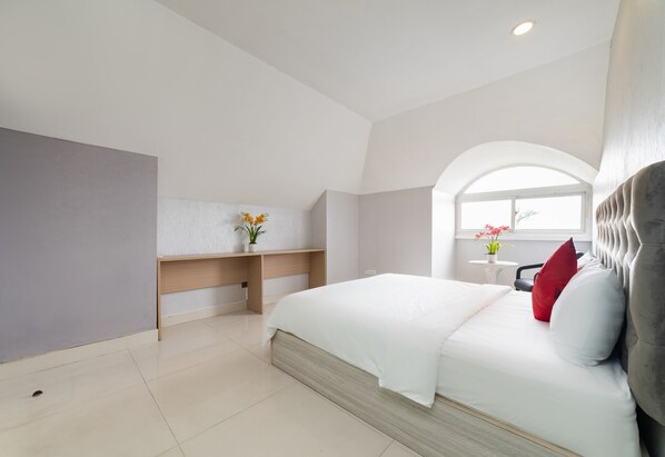 A modern bedroom with a bed, a bedside table, a small desk, and a window with a view.