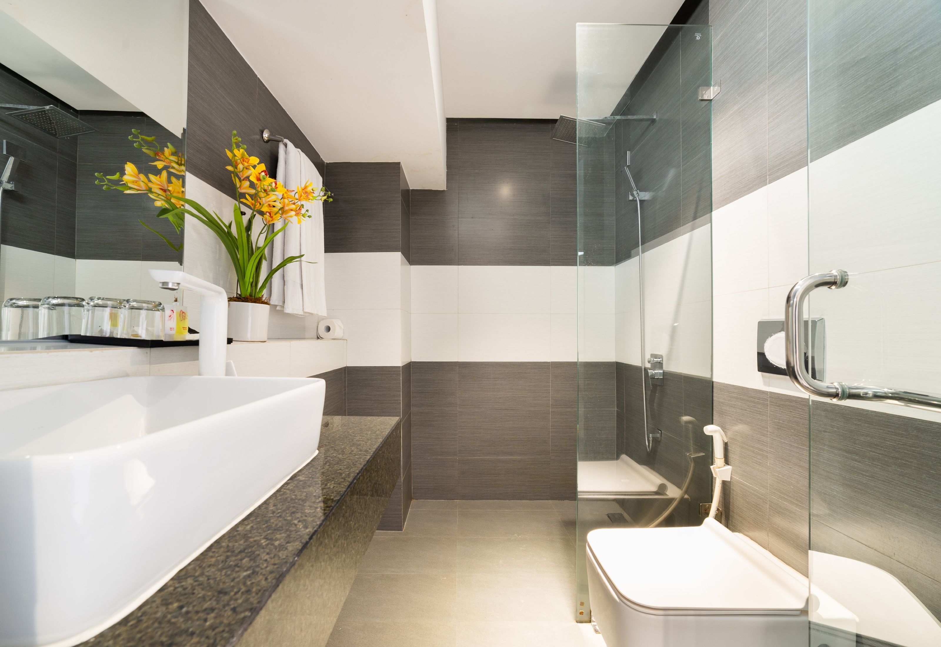 A modern bathroom with a large white bathtub, a glass shower enclosure, and a toilet.