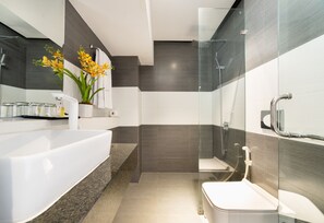 A modern bathroom with a large white bathtub, a glass shower enclosure, and a toilet. - Collection O Sunshine Garden Hotel - Near SECC (Ho Chi Minh City)