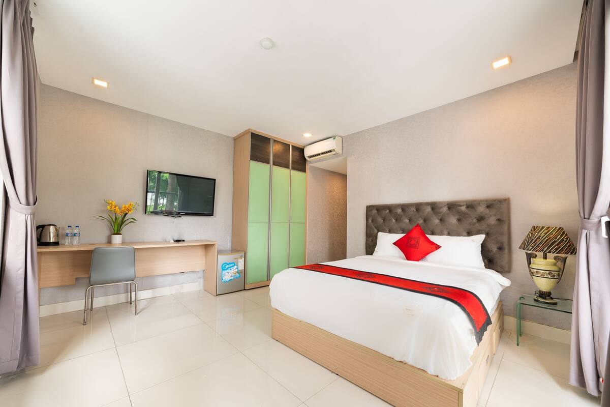 A hotel room with a bed, a desk, a TV, and a wardrobe.