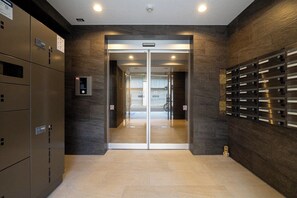 An elevator entrance with a digital control panel, a glass door, and a wall-mounted mail slot. - MAT OSAKA NAGARA (Osaka)