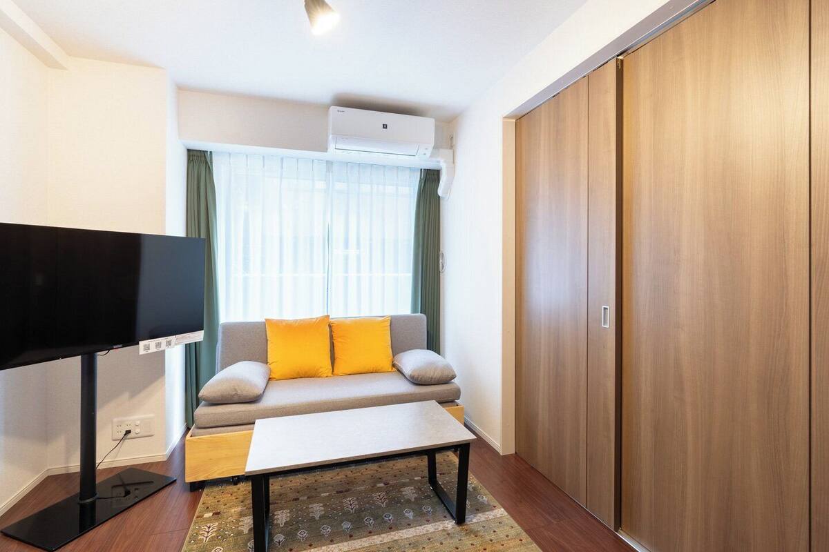 A modern living room with a sofa, a flat-screen TV, and a wooden wardrobe.