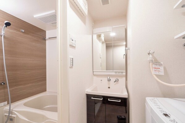 A bathroom with a bathtub, a sink, a mirror, and a toilet.