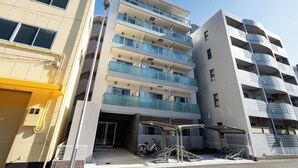 A multi-story residential building with balconies, a bike rack, and a gated entrance. - MAT OSAKA NAGARA (Osaka)
