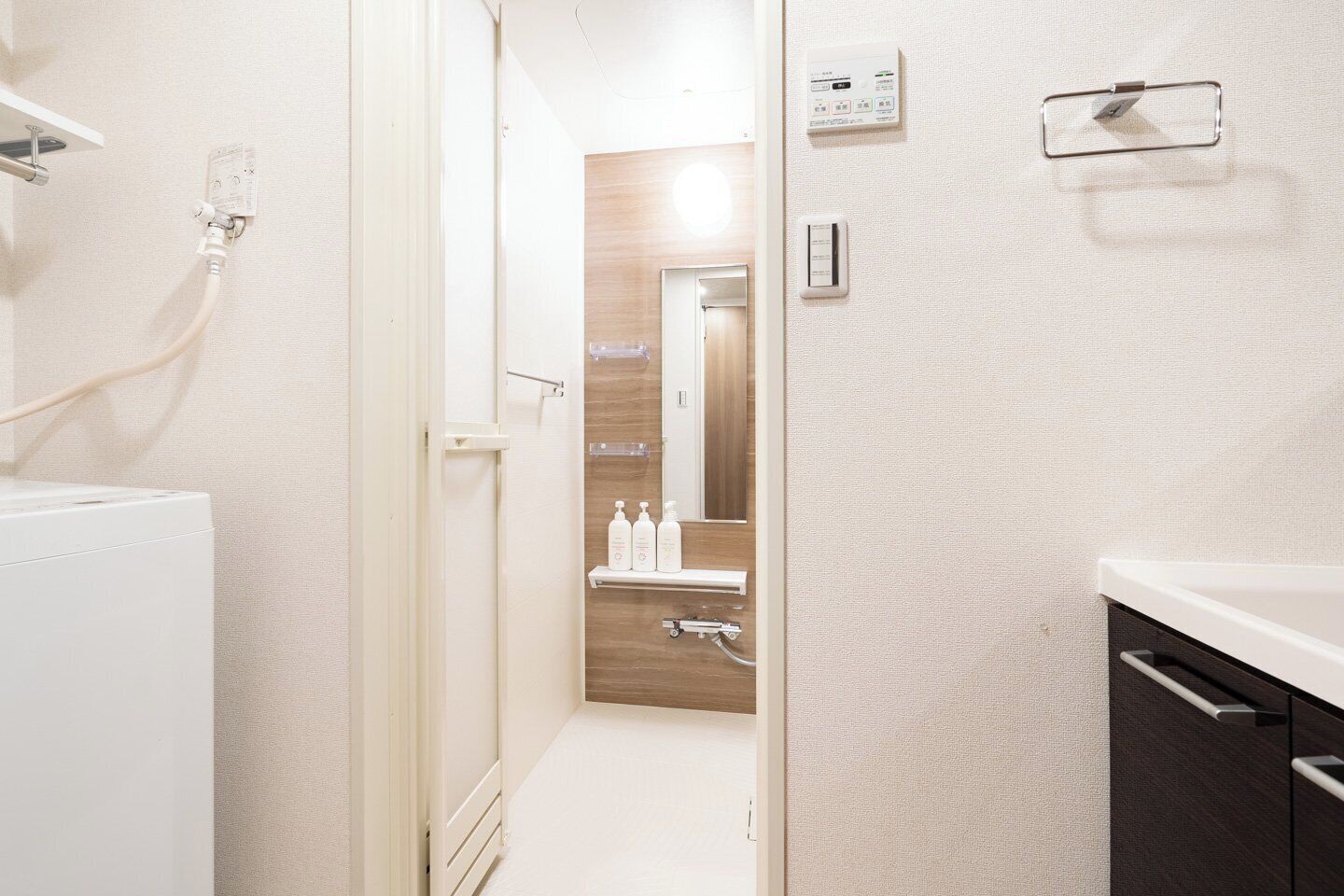 A modern bathroom with a shower, a toilet, and a sink. There are toiletries on the sink and a towel rack on the wall.