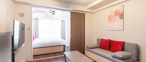 Een moderne hotelkamer met een bed, een bank, een televisie en een plafondventilator.