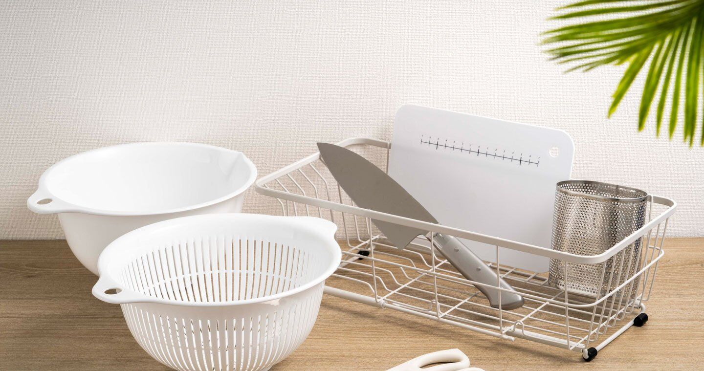 A kitchen setup with a colander, a strainer, and a metal basket on a wooden surface.
