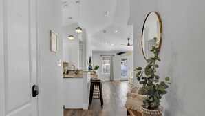 A hallway with a wooden floor, a white door, a bench with a plant, and a mirror on the wall. - Walk to Private Beach+Free golf cart+Private Heated Pool+Pet Friendly (Destin)