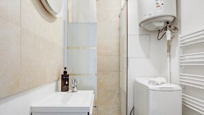 Ein modernes Badezimmer mit einem weißen Waschbecken, einer Duschkabine aus Glas und einem integrierten WC.