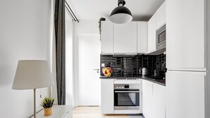 Eine moderne Küche mit weißen Schränken, einer schwarzen Spritzschutzwand und einem eingebauten Backofen.