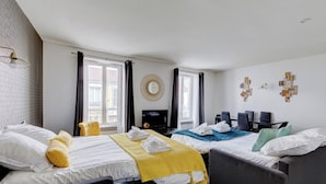 Une chambre d’hôtel avec deux lits, une télévision, un bureau avec des chaises et un mur décoré de pièces de puzzle.