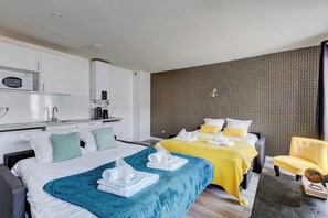 A hotel room with two beds, a kitchenette, and a patterned wall.