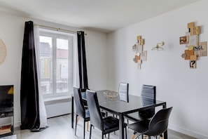 Ein moderner Essbereich mit einem Glastisch, schwarzen Stühlen und Blick auf die Stadt durch ein großes Fenster.