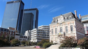 Un paysage urbain avec des gratte-ciel modernes et un bâtiment historique doté d’une tour horloge.