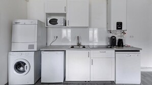 Une cuisine compacte équipée d’un lave-linge, d’un lave-vaisselle, d’un four à micro-ondes et d’une machine à café.