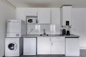 A compact kitchen with a washing machine, dishwasher, microwave, and a coffee maker.