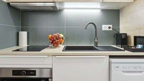 Een moderne keuken met lichte houten kastjes, een RVS vaatwasser en een oven.