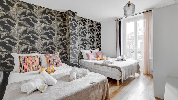 Quarto de hotel com duas camas, uma janela grande e vista para a cidade.