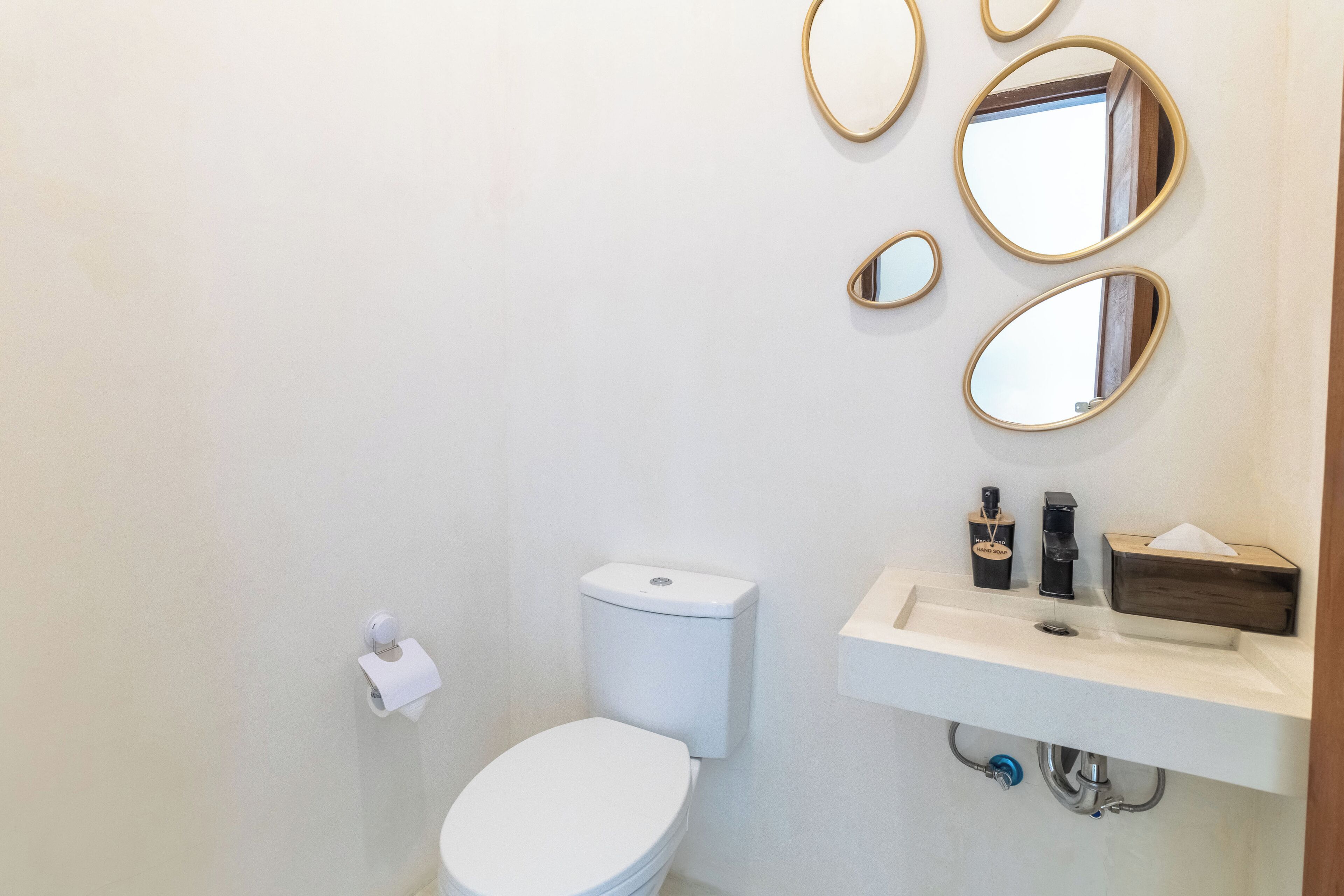 Een badkamer met toilet, wastafel en drie spiegels.