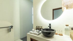 A modern bathroom with a large round mirror, a black basin, and neatly folded towels. - Villa Joba by Pertama Stay (Canggu)