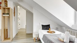 A bedroom with a bed, a bedside table, a tray with breakfast, and a staircase leading to another room. - TheBlueStay 136 - Beautiful Duplex Apartment (Paris)