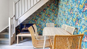 A staircase with a white railing leading to a dining area with wicker chairs and a table. - TheBlueStay 136 - Beautiful Duplex Apartment (Paris)