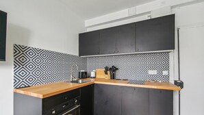 Eine kompakte Küche mit Holzarbeitsplatte, schwarzen Schränken und einer gemusterten Spritzschutzwand.