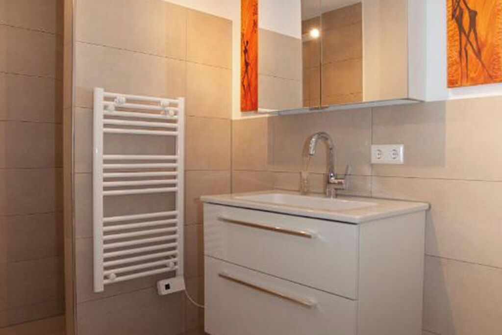 A bathroom with a white sink, a mirror above it, and a towel rack to the left.