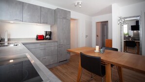 Une cuisine moderne avec des meubles de couleur grise, une table à manger en bois et un grille-pain rouge.