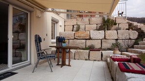 Un espace extérieur aménagé avec une table et des chaises, un mur en pierre et une vue sur une colline.