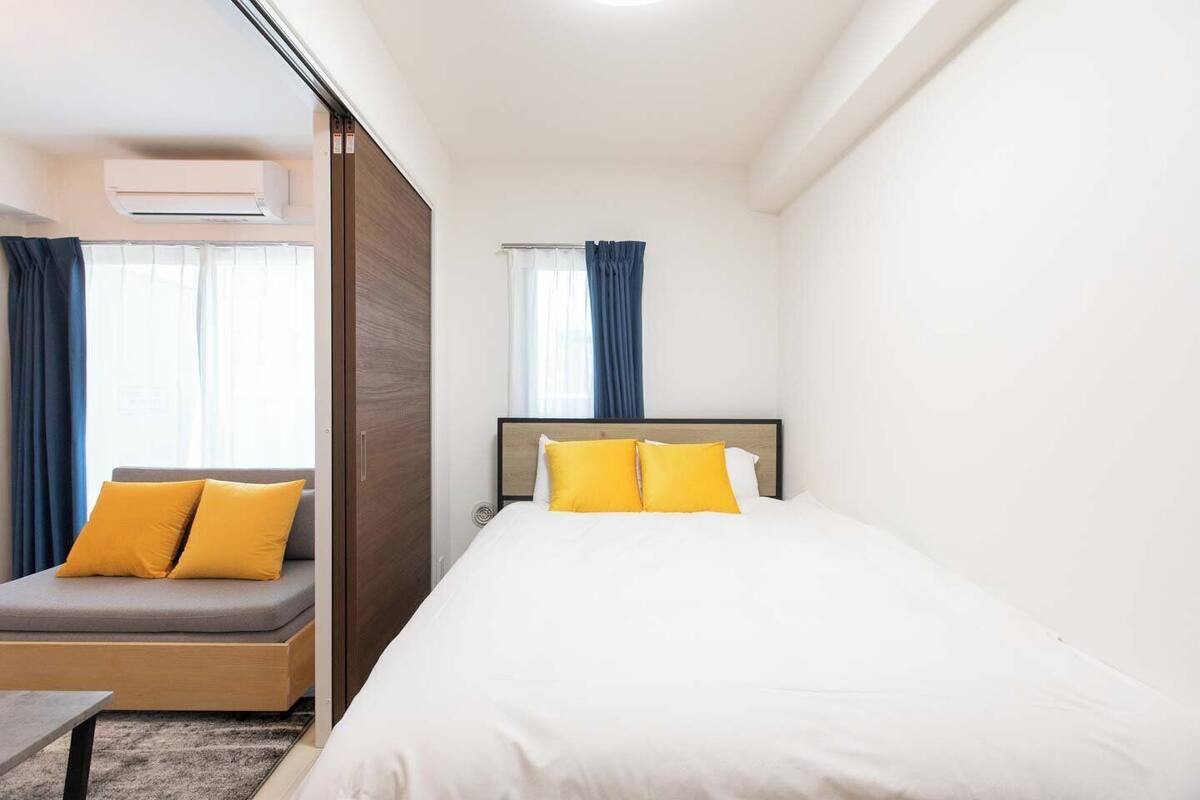 A hotel room with a bed, a sofa, and a window with curtains.