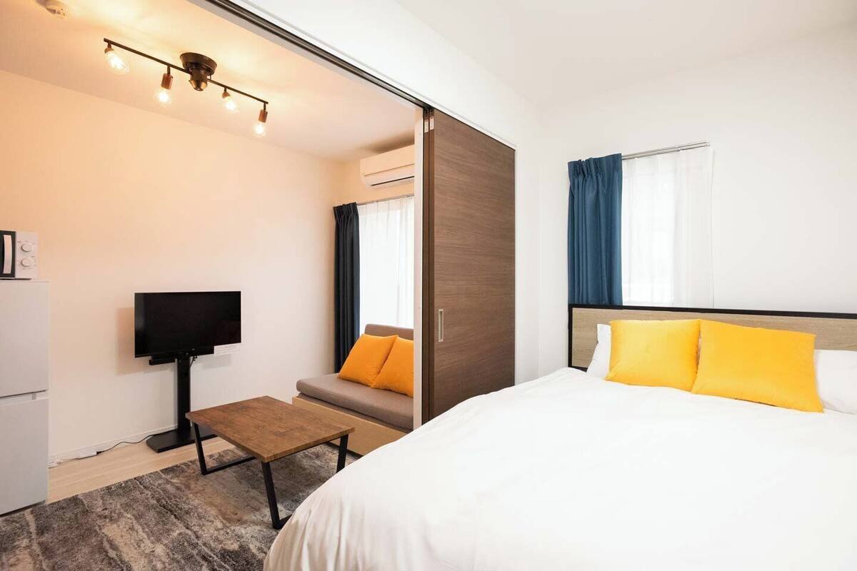 A hotel room with a bed, a TV, a sofa, and a desk.