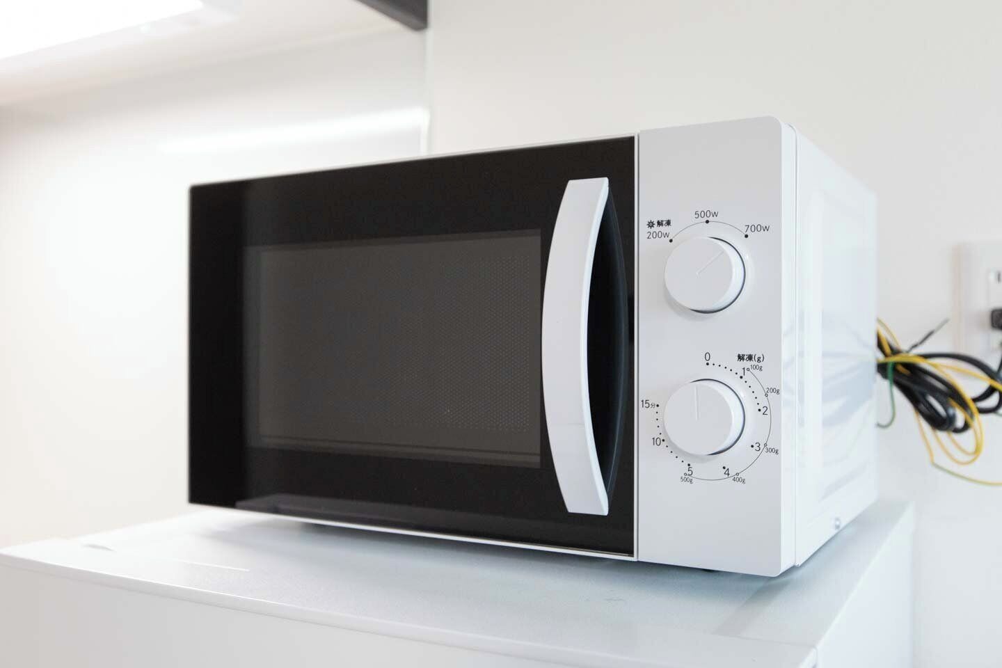 A microwave oven with a digital display and multiple control knobs.