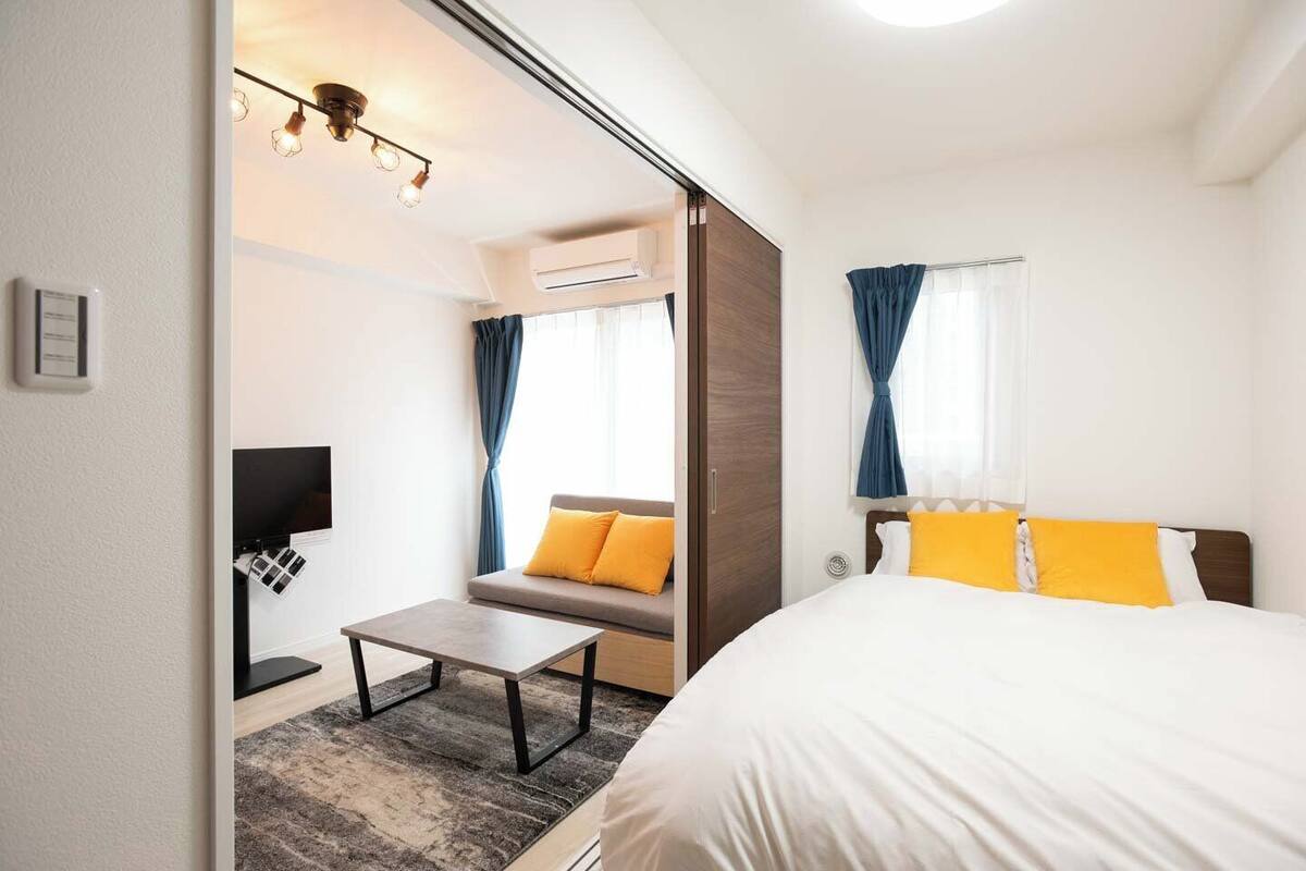 A hotel room with a bed, a sofa, a small table, and a TV.