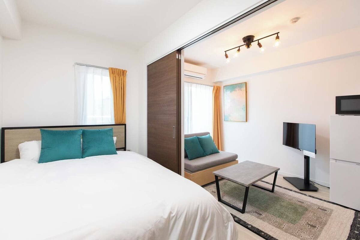 A hotel room with a bed, a sofa, a TV, and a small table.