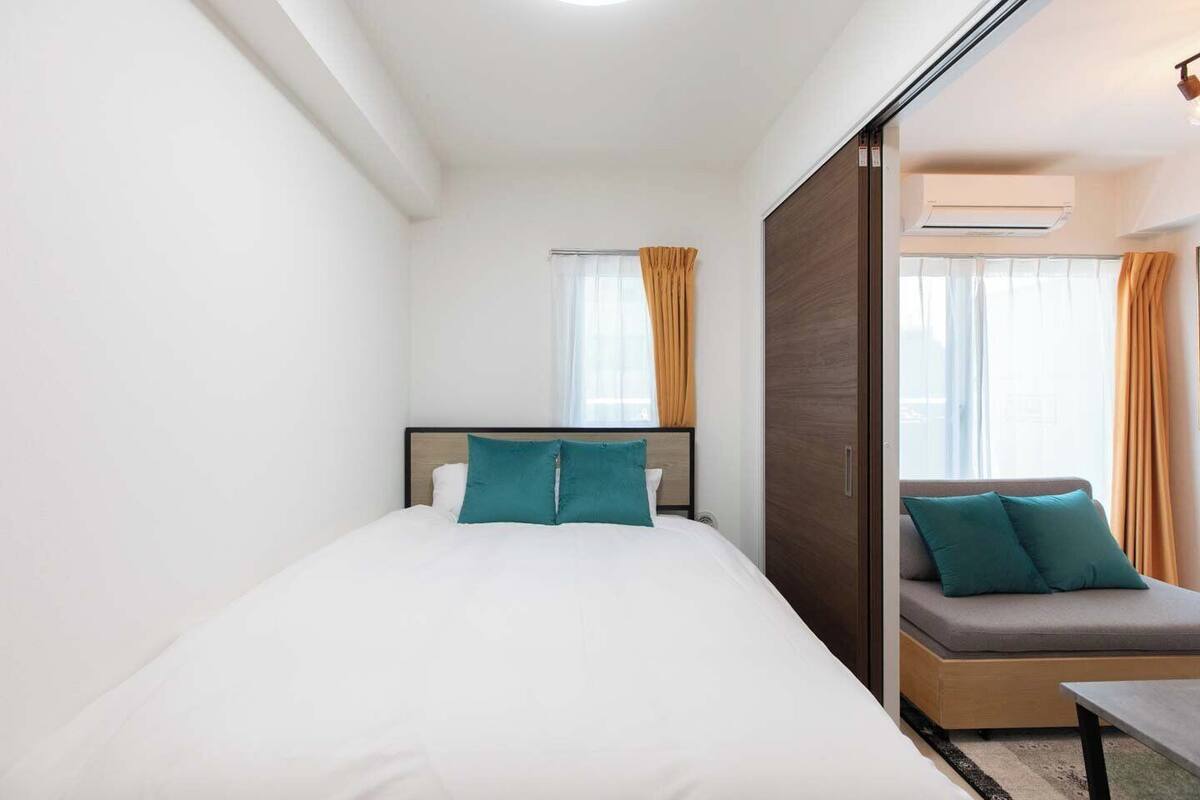 A hotel room with a bed, a sofa, and an air conditioning unit.